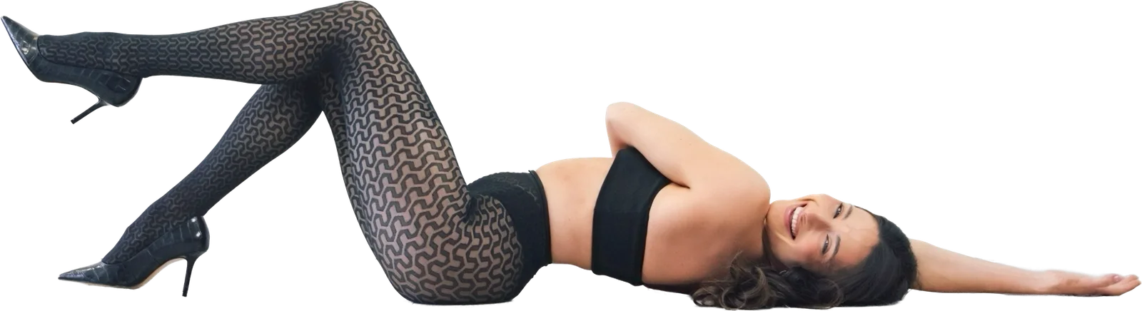 Rita Mc Donnell lying across the studio floor in heels, legs raised mid pose, laughing